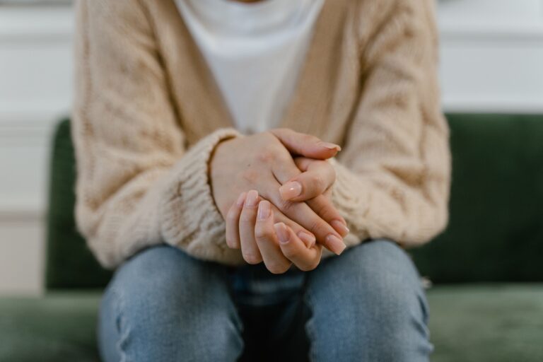 Persona seduta con le mani intrecciate in un momento di tensione emotiva